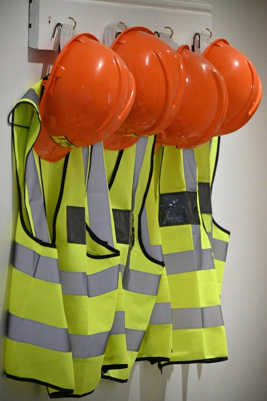 Hard hats and hi-vis vests on hooks in a site store, the point at which an employer's duty of care starts